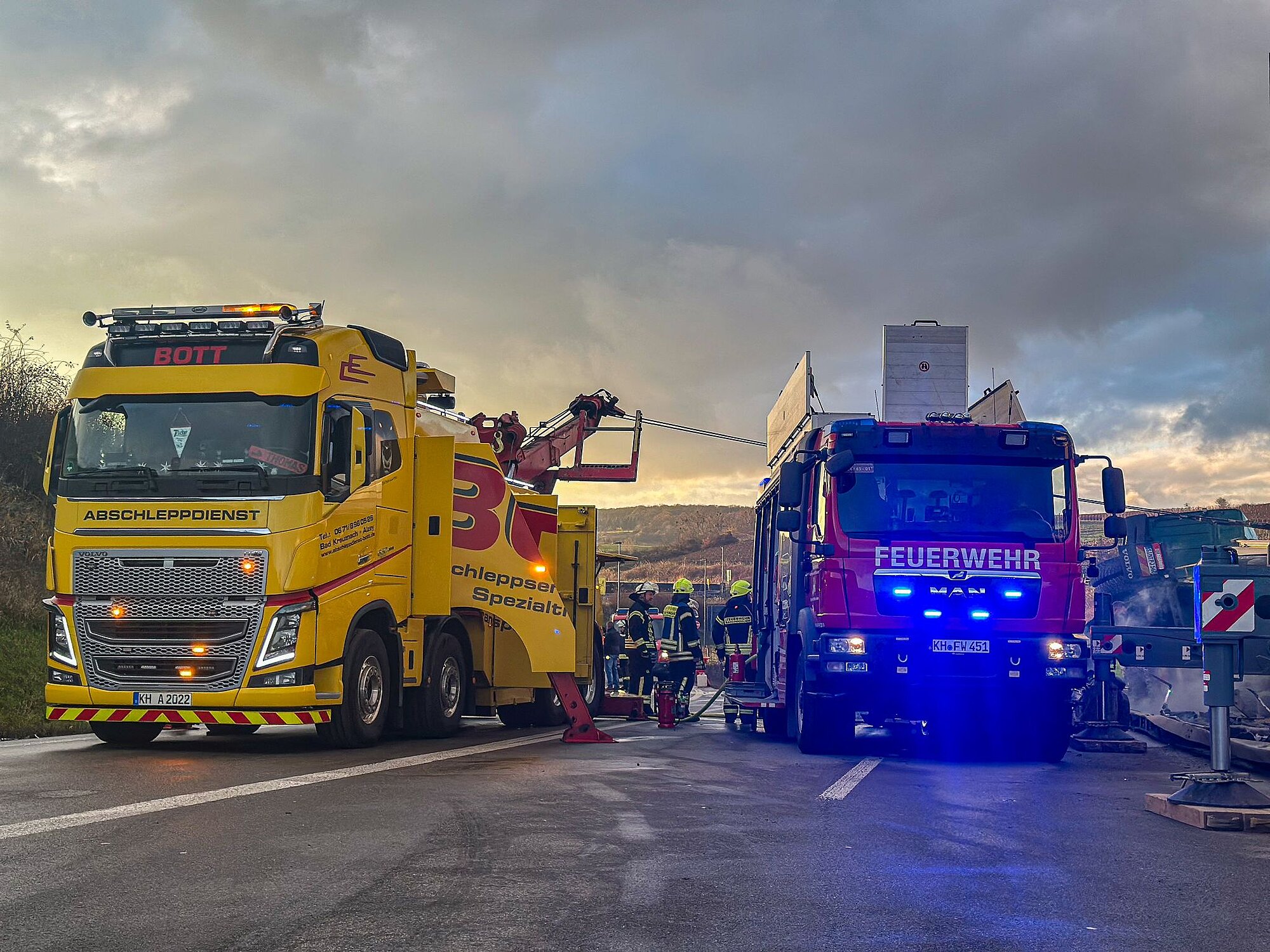 Bergungsszene mit gelbem Abschlepp-Lkw der Firma Bott und Feuerwehrfahrzeug im gemeinsamen Einsatz